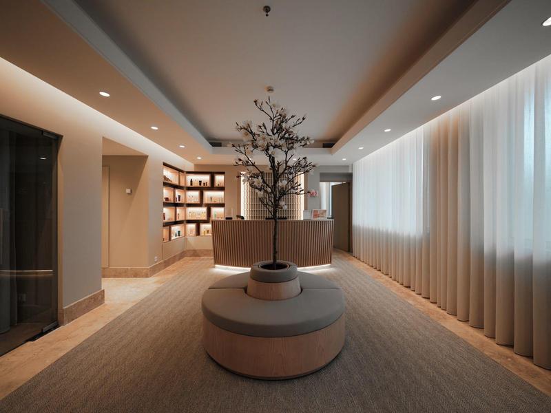 Jasne lobby hotelowe z okrągłą ławką, nowoczesnymi półkami i minimalistyczną dekoracją.