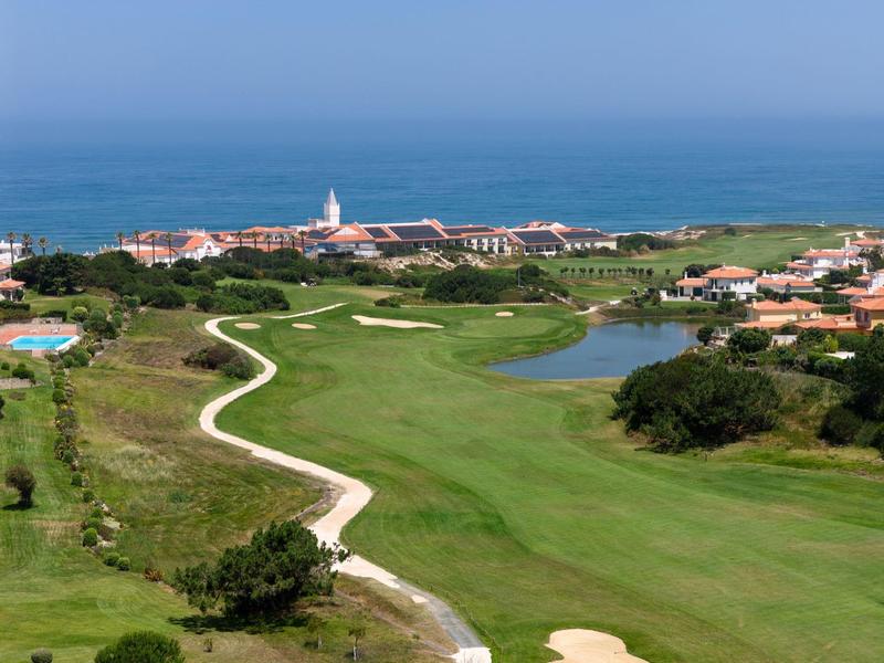 Widok na pole golfowe z widokiem na morze i budynki w tle