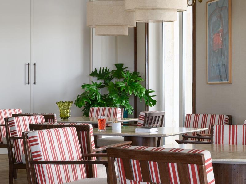 Nowoczesna jadalnia z krzesłami w paski, dużym stołem i zieloną rośliną w jasnym pomieszczeniu