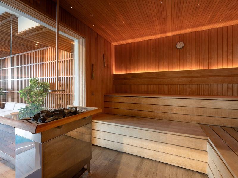 Nowoczesna sauna z drewnianą okładziną i dużymi oknami z widokiem na teren zewnętrzny.