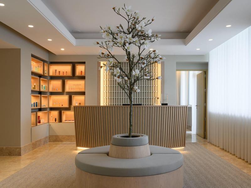 Nowoczesna recepcja hotelowa z drzewem na środku i podświetlanymi półkami w tle
