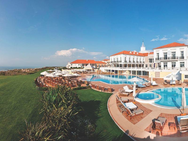 Luksusowy ośrodek z basenami, leżakami i dużym zielonym trawnikiem pod czystym niebem.