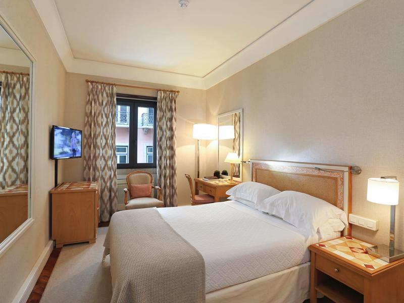 Bright hotel room with double bed, two nightstands, and TV near the window.