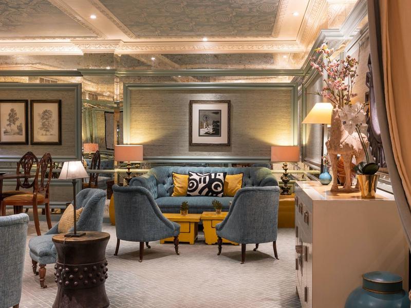Elegant living room with blue armchairs, decorative pillows, and soft lighting in a hotel.