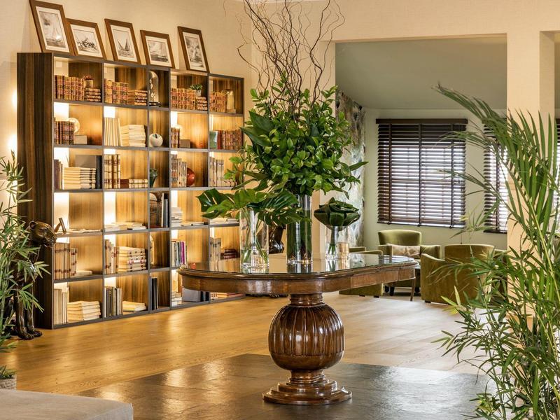 Elegant hotel lobby with decorative shelving, floral arrangement, and comfortable seating.