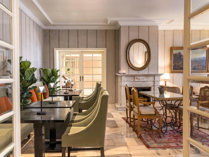Cozy dining area with tables, chairs, and decorative plants in warm lighting.
