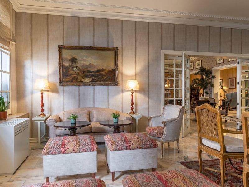 Cozy living area with armchairs, ottomans, rugs, and a view of the adjoining dining space.