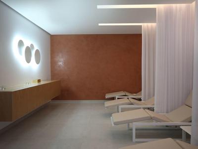 Modern wellness room with long loungers, white curtains, and warm wall lights.