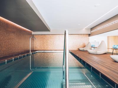 Modern indoor pool with lounge chairs and wooden deck in a hotel