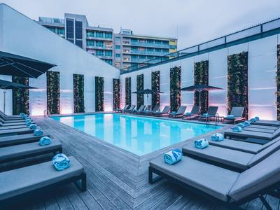 Area piscina esterna moderna con lettini e pareti verdi verticali sotto un cielo limpido.