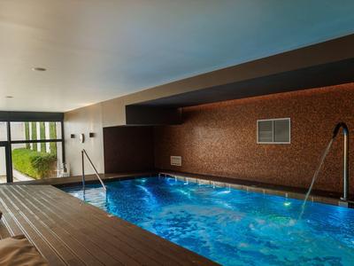 Indoor area with illuminated swimming pool and wooden ceiling in a hotel.