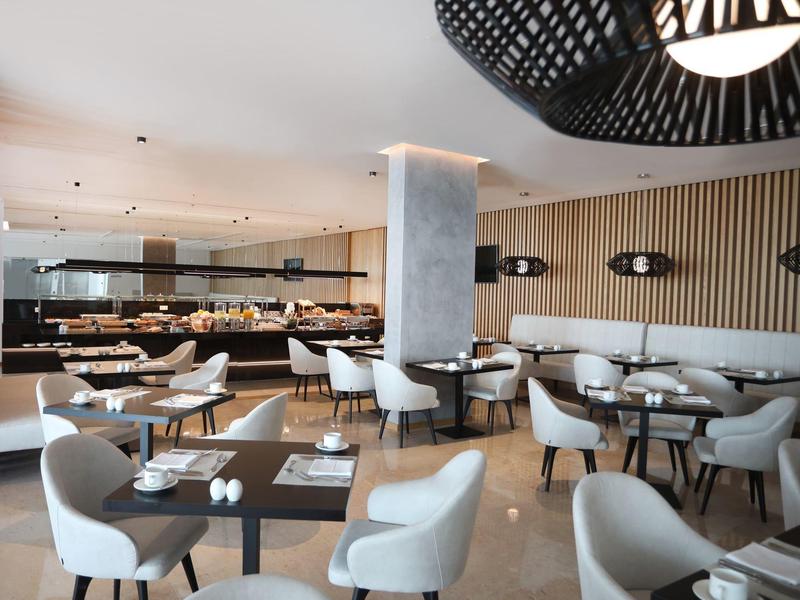 Modern restaurant with grey chairs, wooden tables, and minimalist decor.