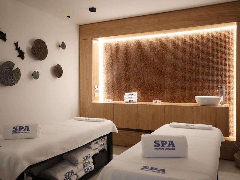 Modern spa room with two treatment beds and ambient lighting.