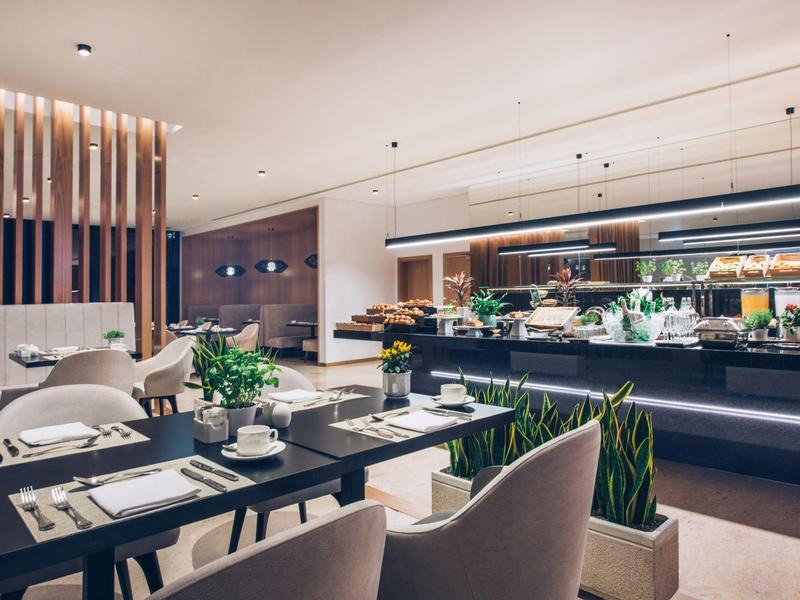 Modern restaurant with elegantly set tables and a buffet area.