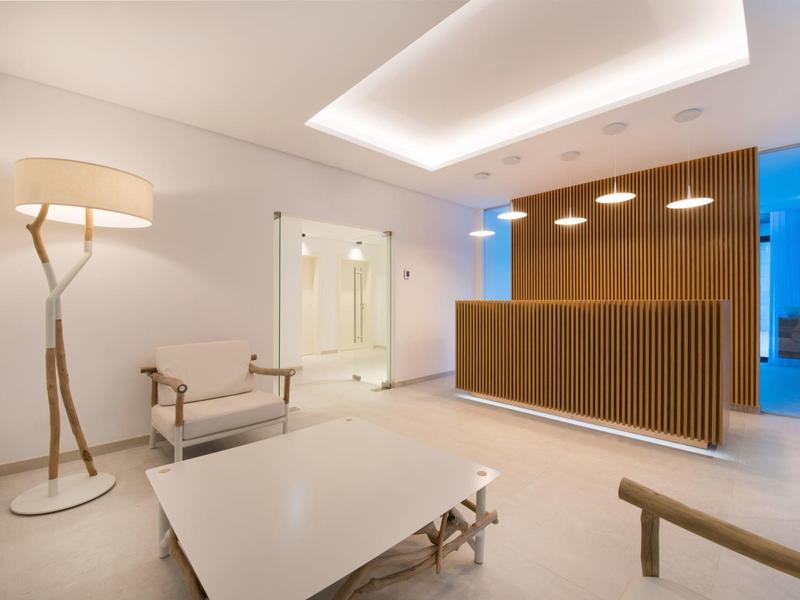Modern hotel lobby with wooden reception desk, comfortable chairs, and stylish lighting.
