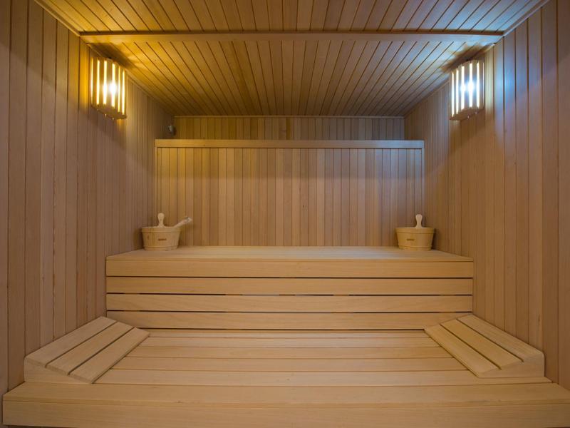 Interior of a sauna with wooden paneling and two wooden buckets on the upper bench.