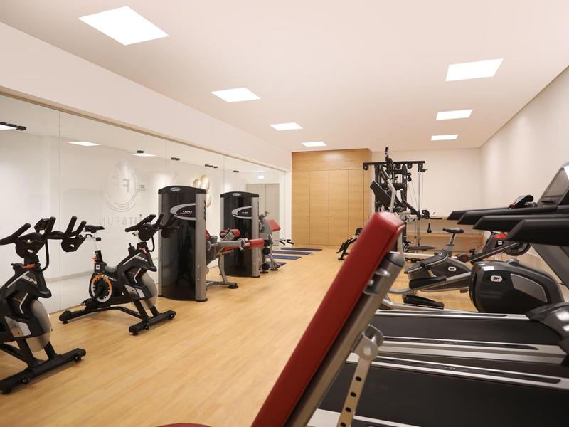 Modern gym with equipment for cycling, strength training, and treadmills