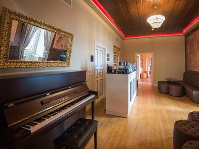 Elegantní hotelová hala s pianem, posezením a lustrem.