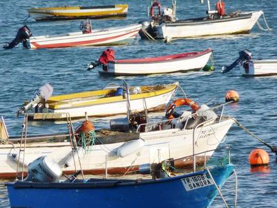 Několik malých lodí klidně pluje na modré mořské vodě.