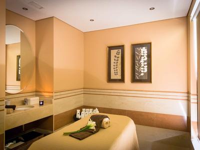 Klidná místnost s masážním stolem, teplými zdmi a dekorativními obrazy.