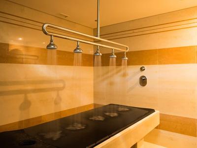 Moderní parní sprchová zóna s několika tryskami a teplými béžovými tóny.