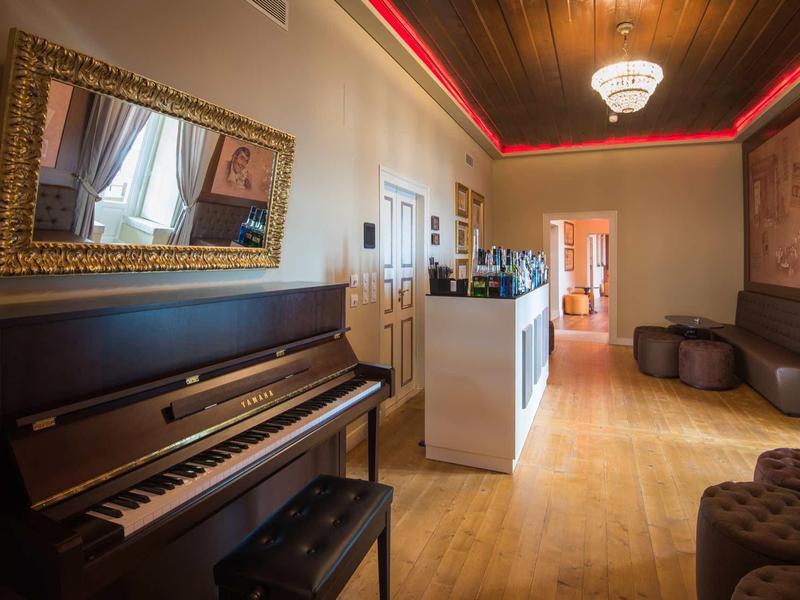 Elegantní hotelová hala s pianem, posezením a lustrem.