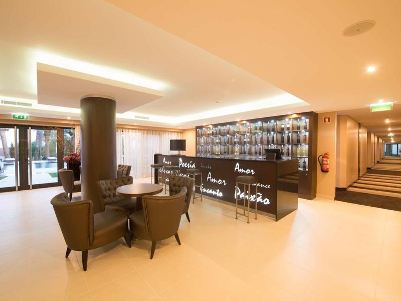 Moderní hotelový lounge s posezením a barem v světlém prostředí.