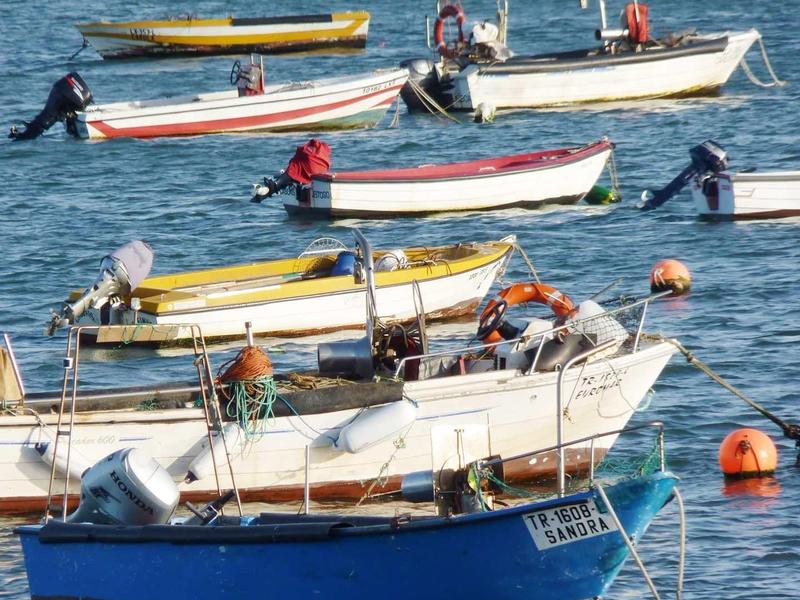 Několik malých lodí klidně pluje na modré mořské vodě.