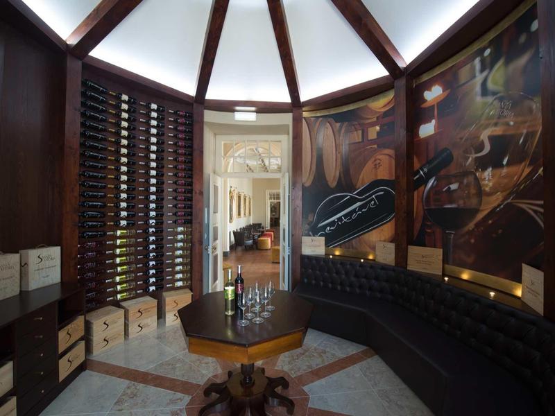 Elegantní vinný sklep s zaoblenou dřevěnou lavicí a regálem na lahve.