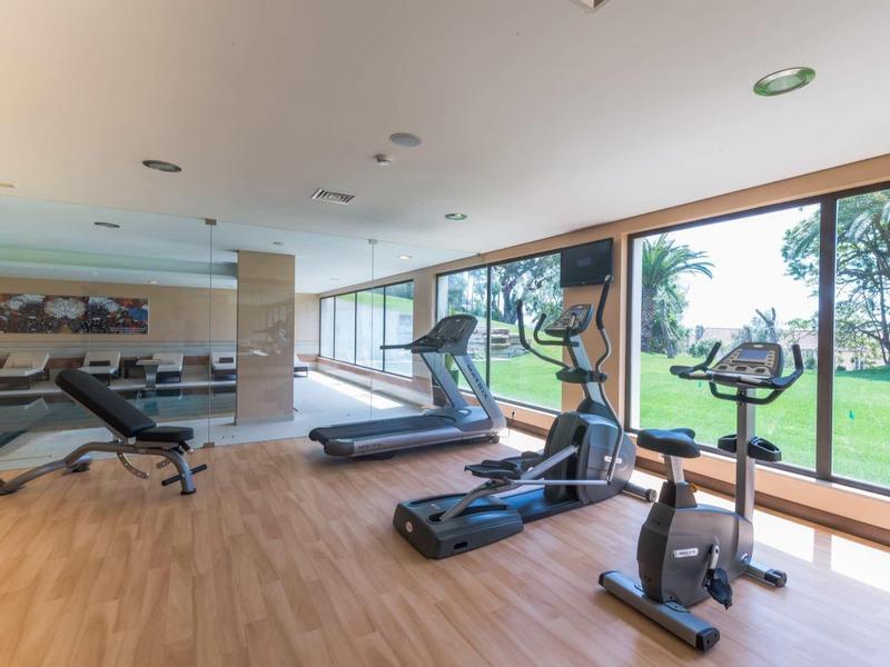 Moderní fitness místnost s běžeckými pásy, rotopedy a velkými okny s výhledem do zahrady.