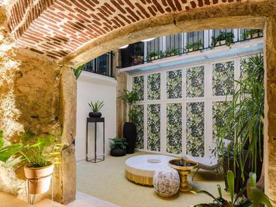 Cortile accogliente con texture erbosa, piante e area salotto sotto un arco in mattoni.