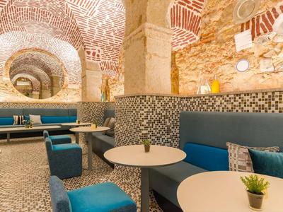 Accogliente zona lounge con panche blu e tavoli in una stanza di pietra elegante.