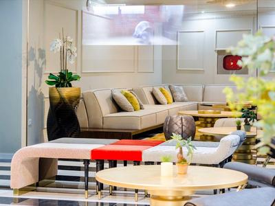 Area lounge di un hotel moderno con divani comodi e piante decorative.