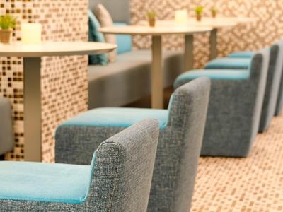 Fila di sedie blu-grigie confortevoli davanti a tavoli bianchi in un ristorante di un hotel.