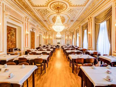 Grande sala da pranzo elegante con accenti dorati e lampadari in un hotel.