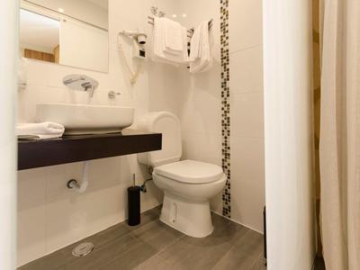 Bagno compatto con wc bianco, lavabo, grande specchio e asciugacapelli.