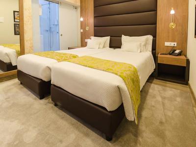 Camera d'hotel moderna con letto matrimoniale, comodino e grande specchio.