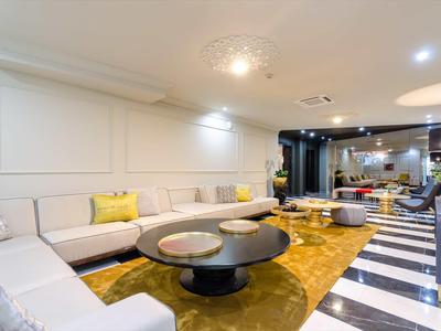 Area lounge moderna dell'hotel con divano bianco, tappeto colorato e tavoli rotondi.