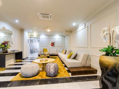 Area lounge di hotel moderna con sedute eleganti, tappeto e piante decorative.