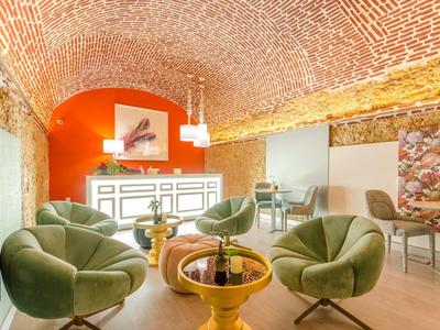 Accogliente zona lounge con poltrone verdi sotto una volta in mattoni.