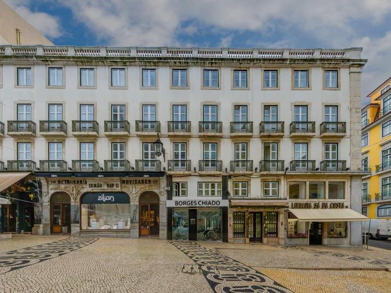 Facciata di un hotel bianco con balconi e caffè su una piazza lastricata