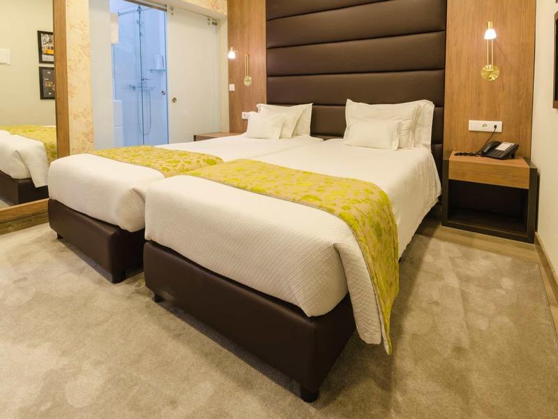 Camera d'hotel moderna con letto matrimoniale, comodino e grande specchio.