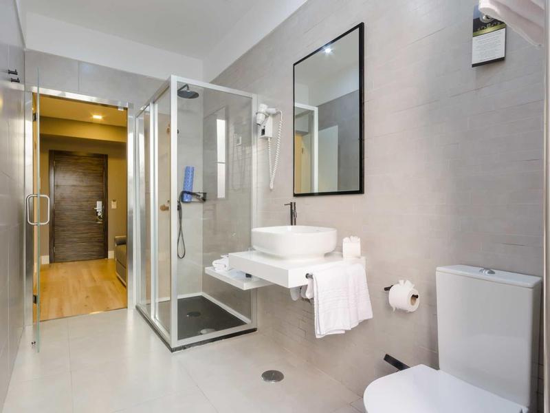 Bagno moderno dell'hotel con doccia in vetro, lavabo e wc in toni chiari.