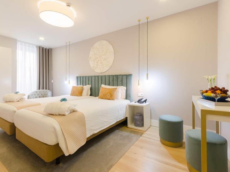 Camera d'hotel moderna con due letti singoli, illuminazione accogliente e arredamento semplice.