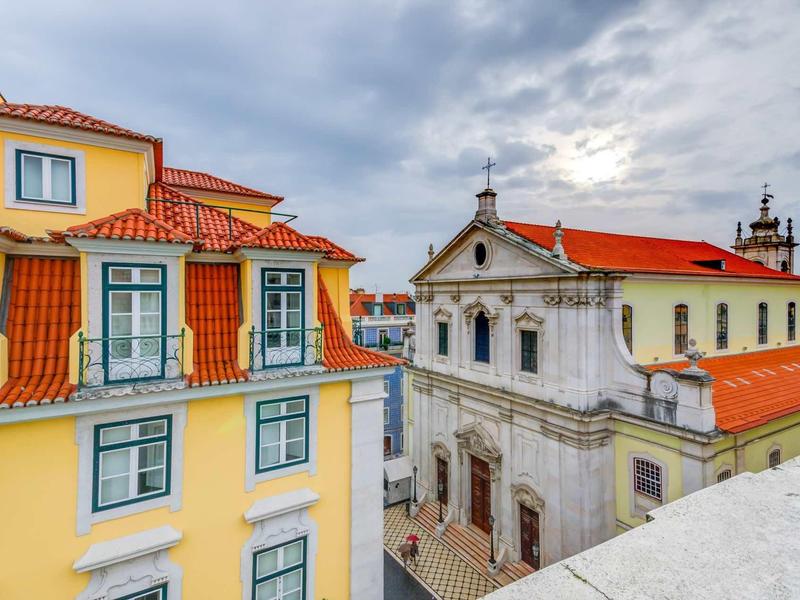 Vista di edifici storici e moderni con tetti rossi sotto un cielo nuvoloso.