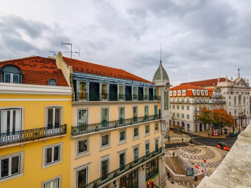 Vista sulla città con edifici gialli, piazza lastricata e cielo nuvoloso
