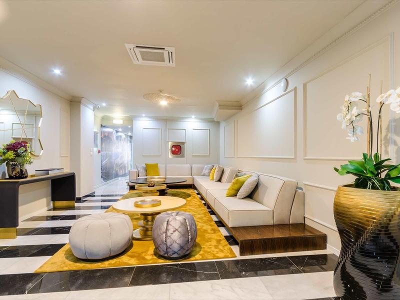 Area lounge di hotel moderna con sedute eleganti, tappeto e piante decorative.