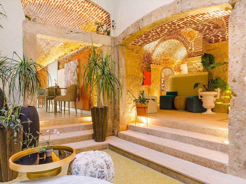 Interno luminoso e accogliente con scale, piante e mobili in legno in un hotel.