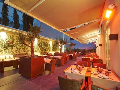 Evening hotel terrace with set tables and warm lighting.