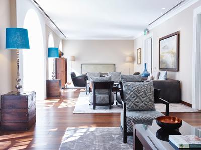 Bright living room with modern furniture, large windows, and blue lamps.